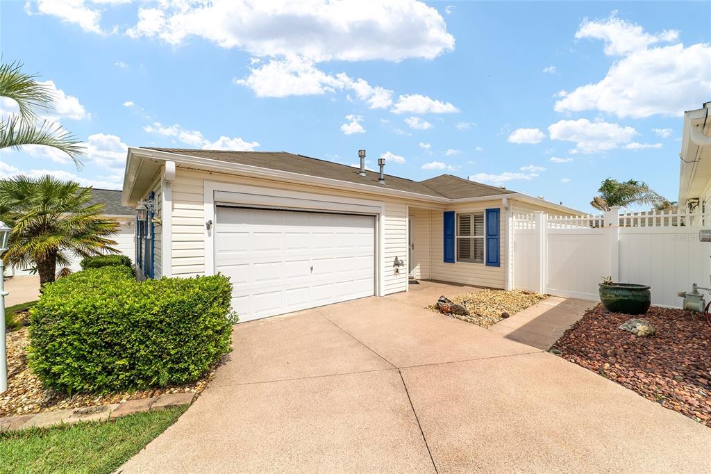 A single-story house with a white garage, blue shutters, and a concrete driveway — 587 AUDREY LANE, THE VILLAGES, FL