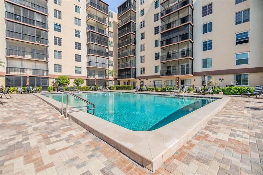 A swimming pool sits in the courtyard of a multi-story apartment building with screened balconies — 2901 26TH STREET W UNIT 606, BRADENTON, FL