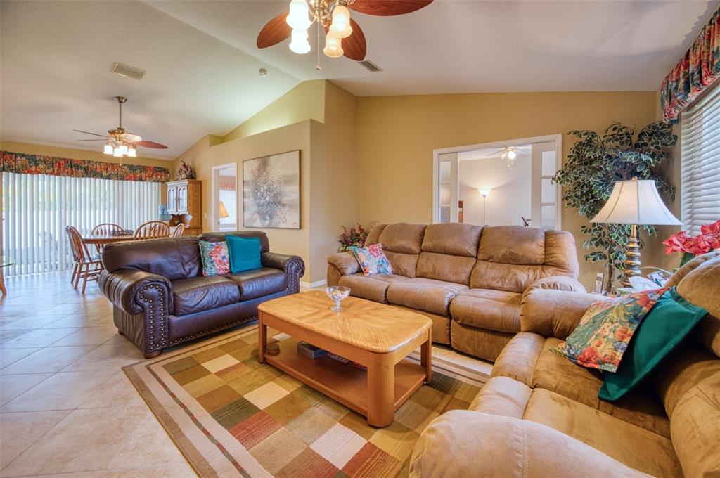 A living room features tile flooring, a plaid area rug, and three brown sofas — 541 FALKLAND ROAD, VENICE, FL