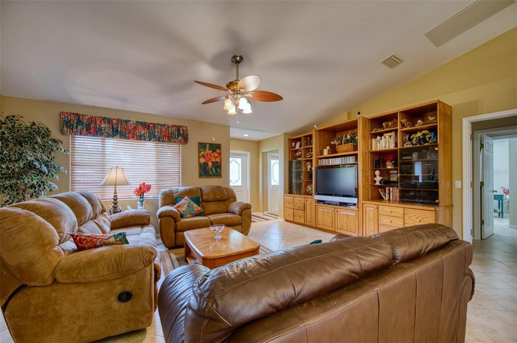 A living room features brown leather furniture, a ceiling fan, and a large wooden entertainment center — 541 FALKLAND ROAD, VENICE, FL