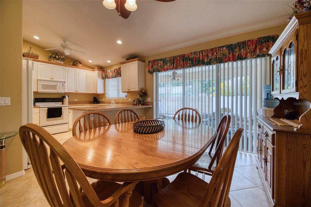 A dining area with a wooden table and chairs sits adjacent to a white kitchen — 541 FALKLAND ROAD, VENICE, FL