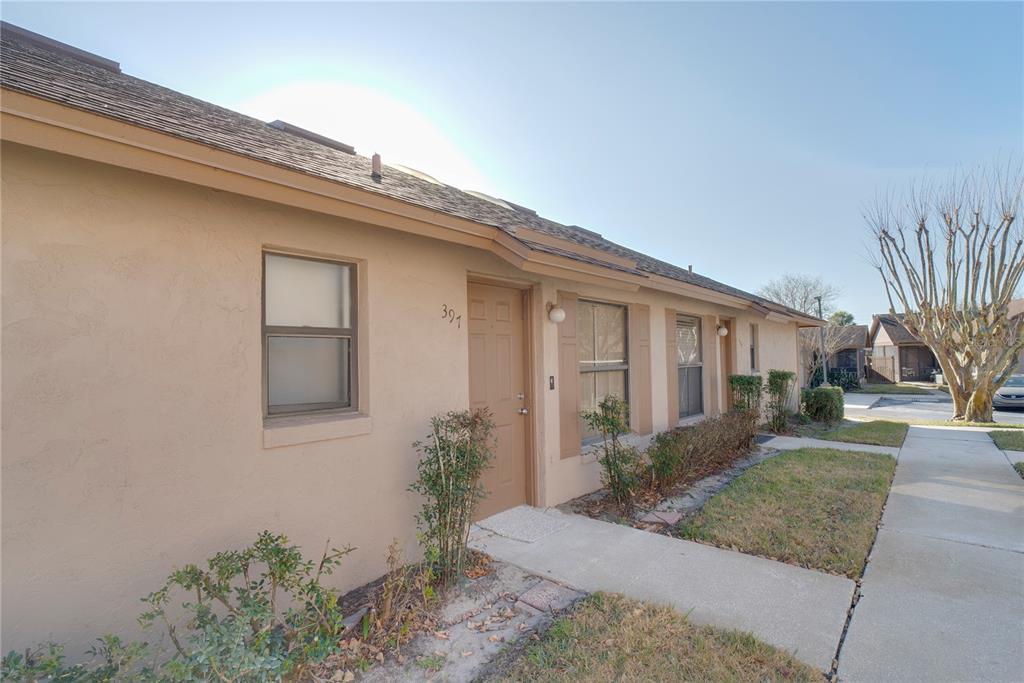 A tan, single-story residential building with a front door, windows, and a concrete walkway — 397 ERON WAY UNIT 42, WINTER GARDEN, FL