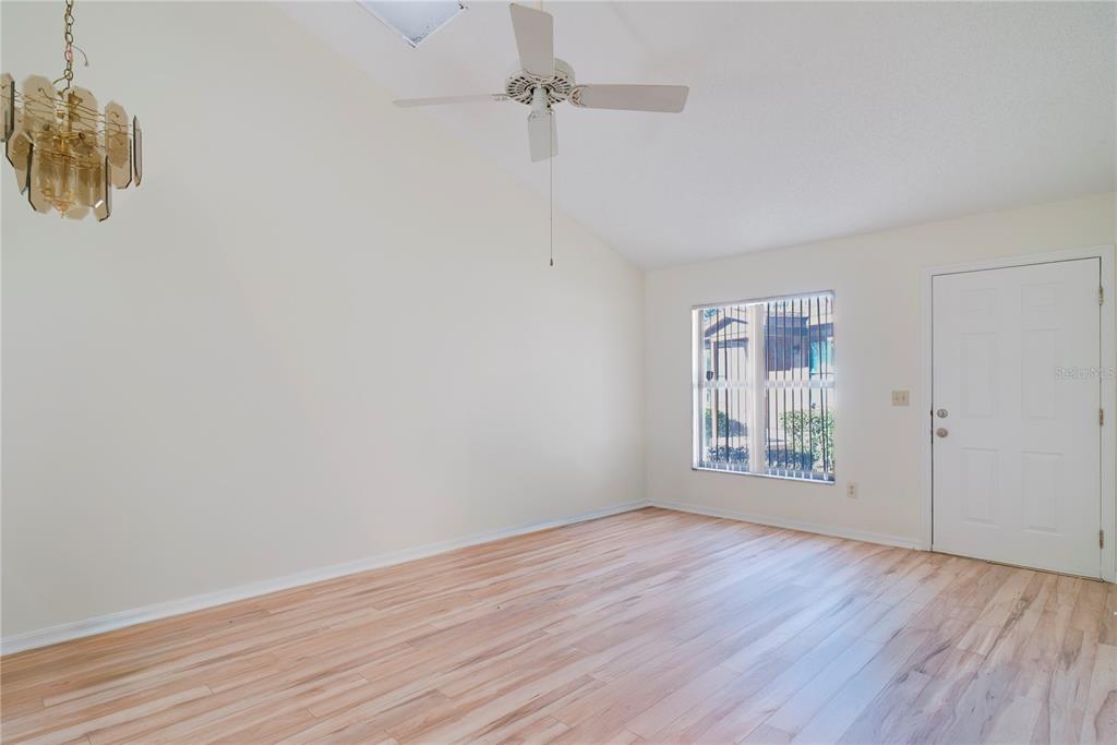 An empty room features light wood flooring, a ceiling fan, and a white entry door — 397 ERON WAY UNIT 42, WINTER GARDEN, FL