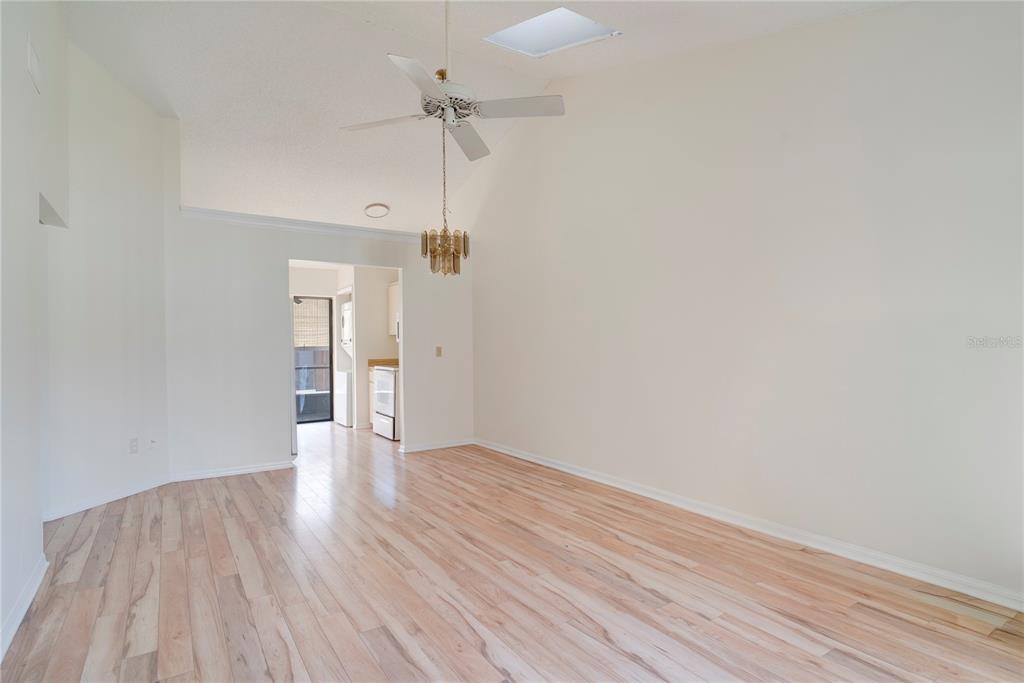 An empty room with light wood flooring, a vaulted ceiling, a ceiling fan, and a chandelier — 397 ERON WAY UNIT 42, WINTER GARDEN, FL