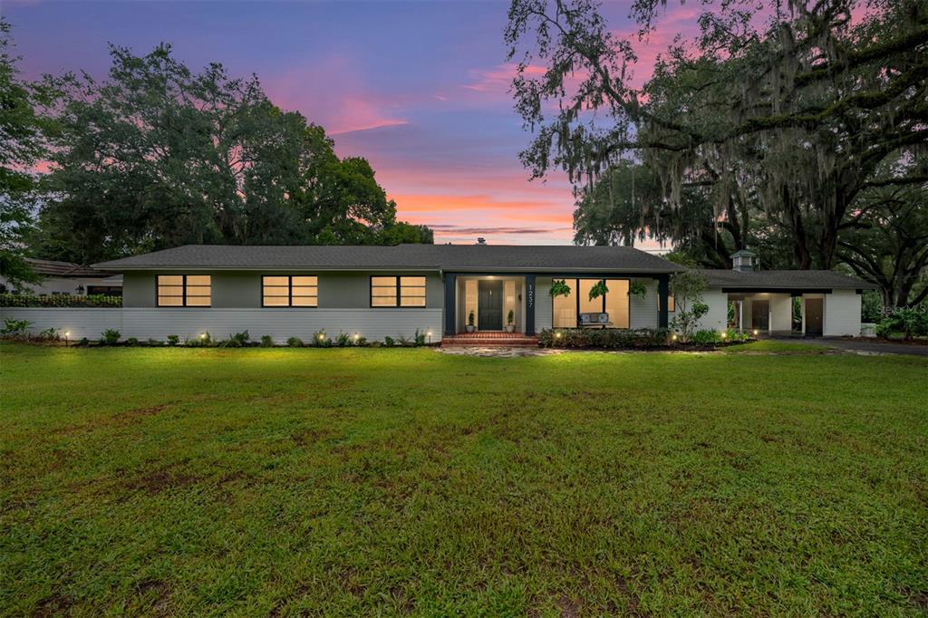 A single-story house with a gray exterior, large windows, and a lawn at sunset — 1237 SE 8TH STREET, OCALA, FL