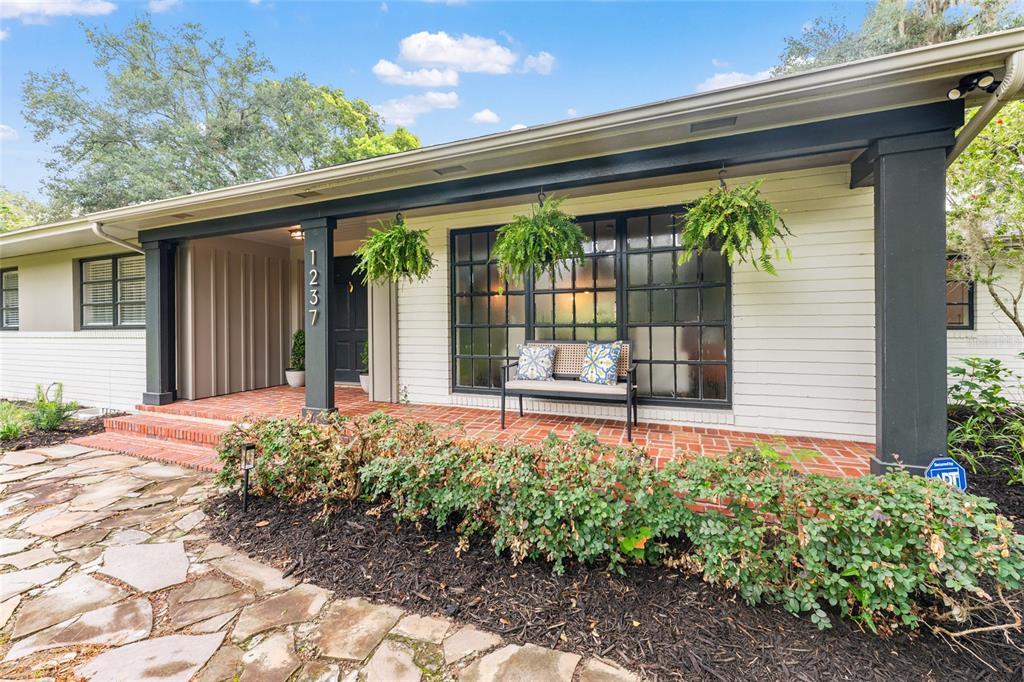 A single-story house exterior features a brick porch, dark trim, and a stone walkway — 1237 SE 8TH STREET, OCALA, FL
