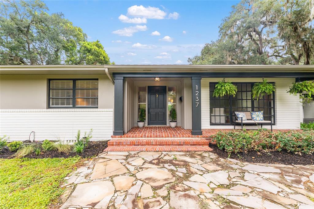 A single-story house with a brick porch, stone walkway, and dark trim around the entrance — 1237 SE 8TH STREET, OCALA, FL