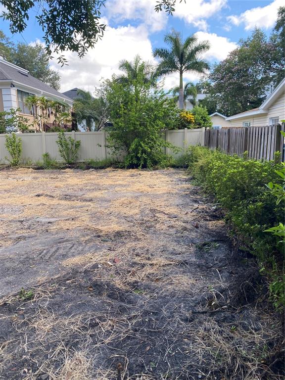 A backyard area features a cleared dirt lot covered in straw with surrounding privacy fences — 2310 S HESPERIDES STREET, TAMPA, FL