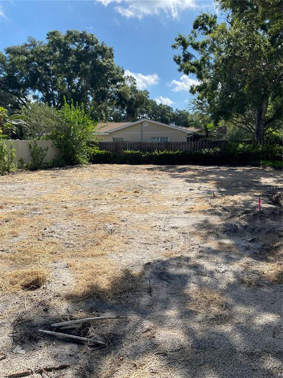 A vacant, sandy residential lot with a fence and a house in the background — 2310 S HESPERIDES STREET, TAMPA, FL
