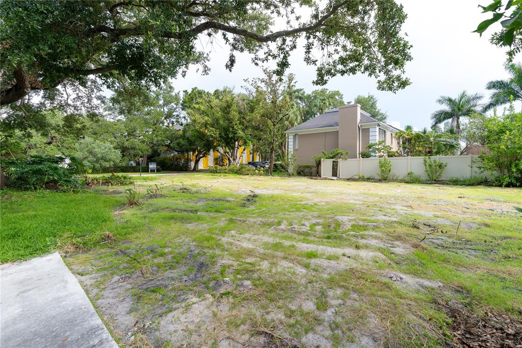 A vacant, grassy lot with scattered trees and a neighboring house in the background — 2310 S HESPERIDES STREET, TAMPA, FL