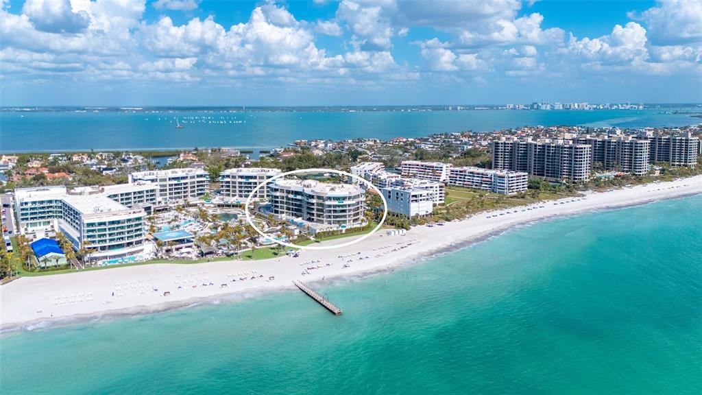 An aerial view of a multi-story beachfront resort building circled on a sandy coastline — 1561 GULF OF MEXICO DRIVE UNIT 403, LONGBOAT KEY, FL