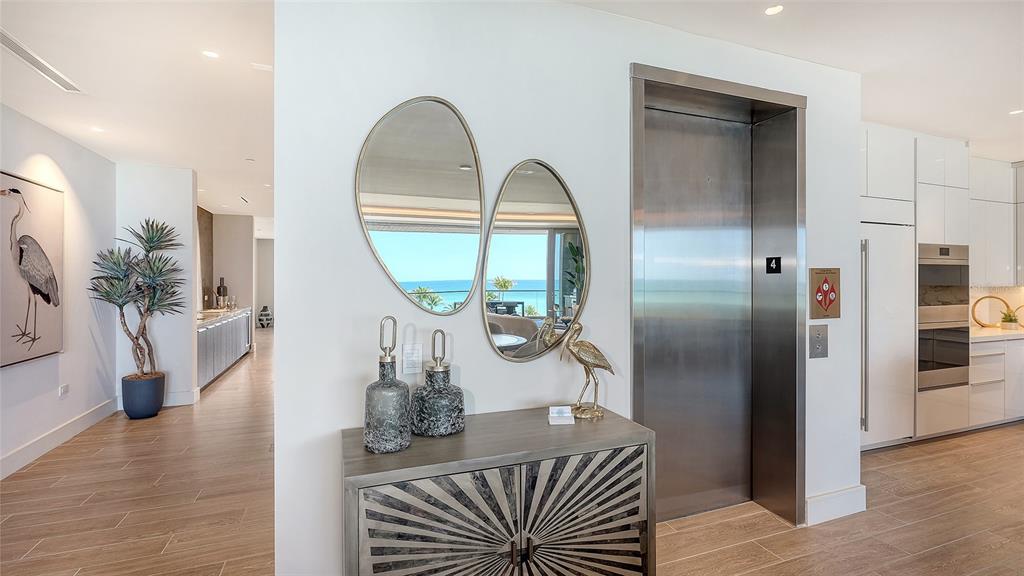 An entryway features a metal elevator, a decorative cabinet, two mirrors, and wood-look flooring — 1561 GULF OF MEXICO DRIVE UNIT 403, LONGBOAT KEY, FL