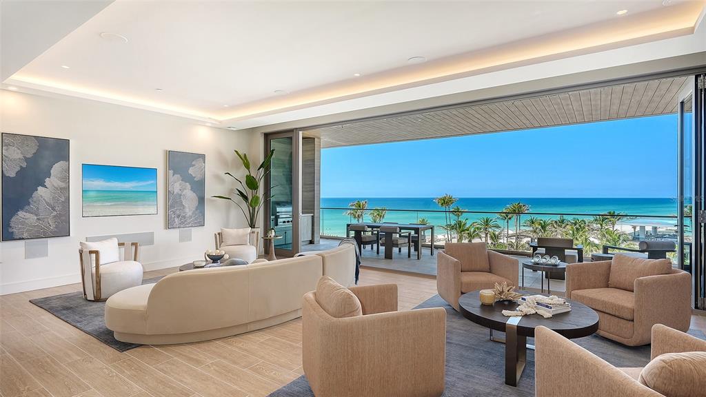 A modern living room features neutral furniture, a large open wall, and a coastal ocean view — 1561 GULF OF MEXICO DRIVE UNIT 403, LONGBOAT KEY, FL