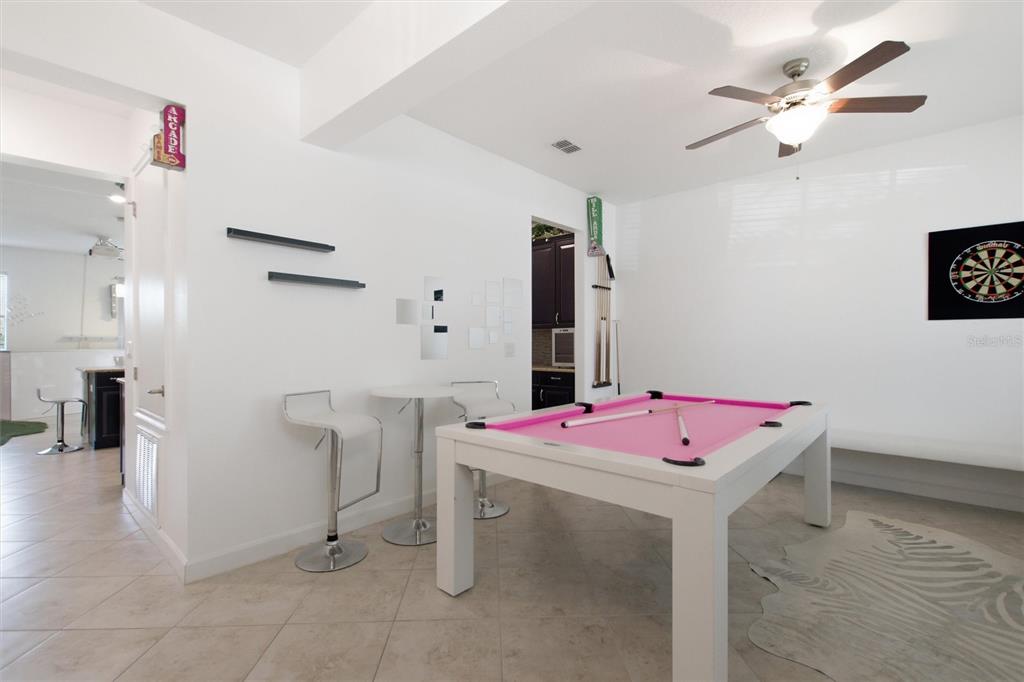 A game room features a pink pool table, a dartboard, and a small bistro table — 1407 PRO SHOP CT, DAVENPORT, FL
