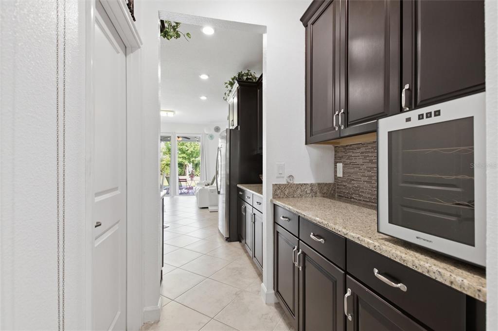 A kitchen butler's pantry features dark wood cabinets, granite countertops, and a built-in wine cooler — 1407 PRO SHOP CT, DAVENPORT, FL