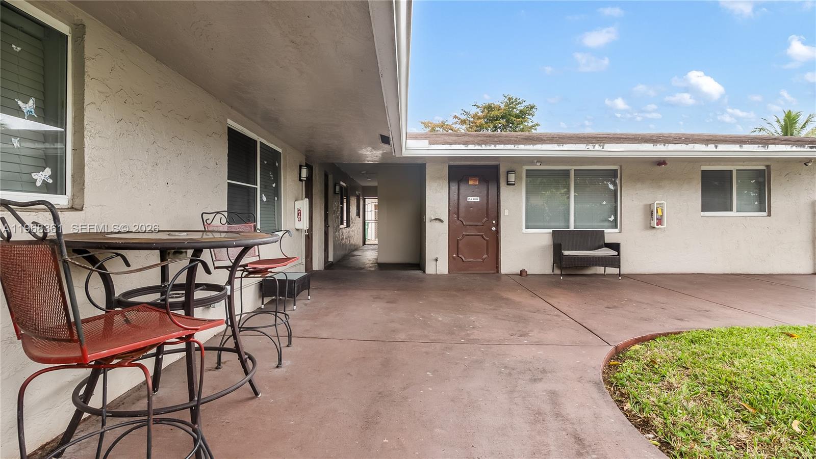 A patio area features a metal table and chairs, a bench, and a brown door — 5940 NW 19th Ct, Lauderhill FL 33313, LAUDERHILL, FL
