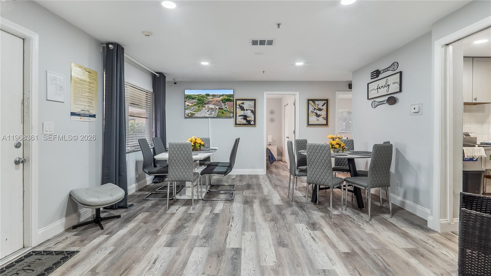 A dining room features two tables with grey upholstered chairs and light wood-look flooring — 5940 NW 19th Ct, Lauderhill FL 33313, LAUDERHILL, FL