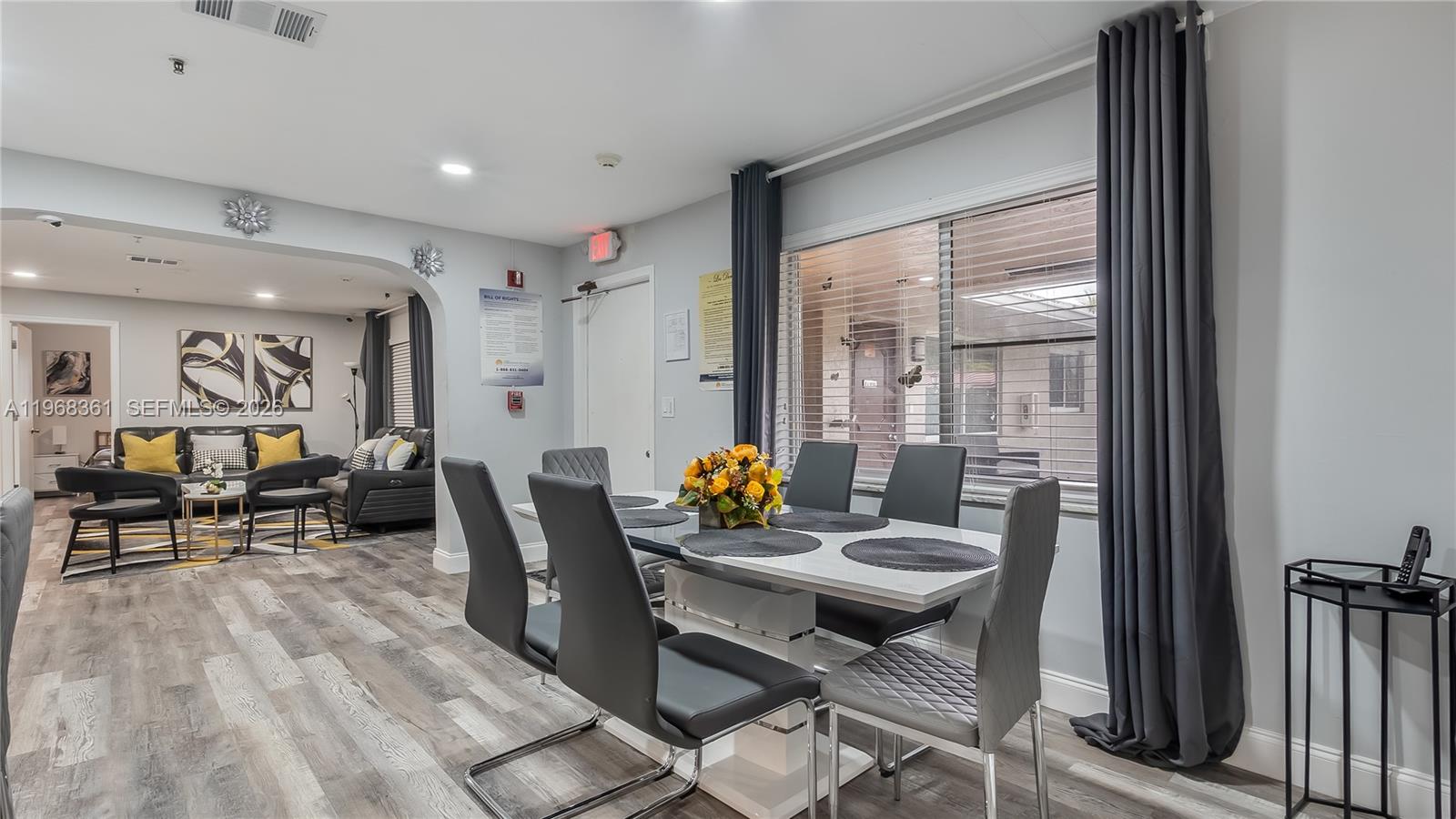 A dining area with a white table and grey chairs opens into a living room — 5940 NW 19th Ct, Lauderhill FL 33313, LAUDERHILL, FL