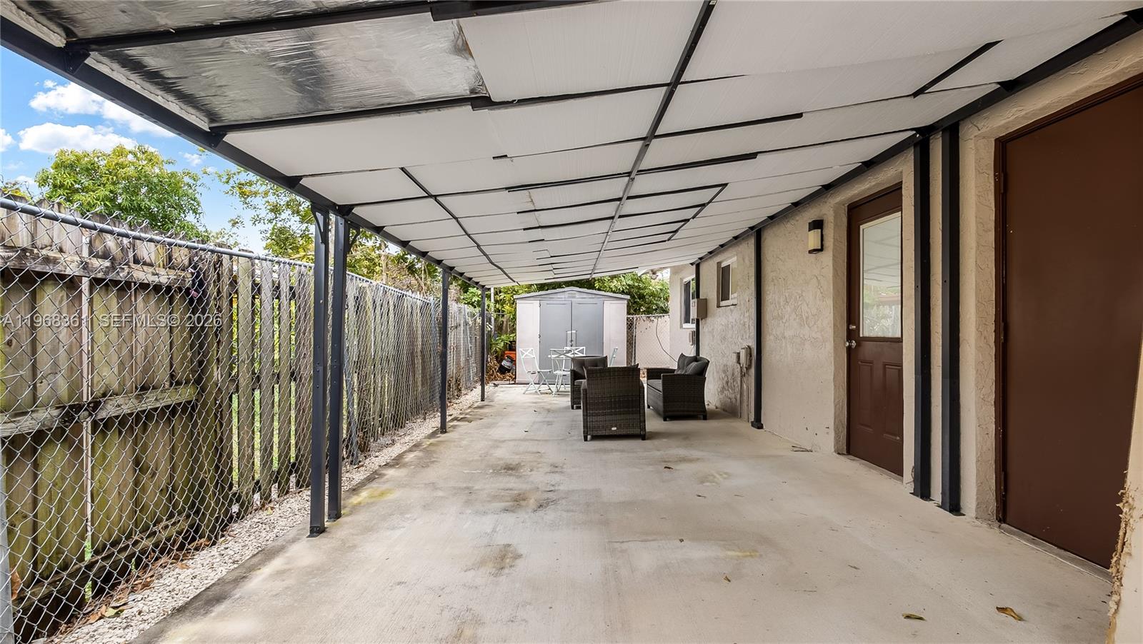 A covered concrete patio features a chain-link fence, outdoor furniture, and two exterior doors — 5940 NW 19th Ct, Lauderhill FL 33313, LAUDERHILL, FL