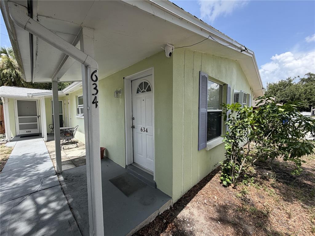 The exterior of a light green house features a covered porch and a white door — 634 DOGWOOD COURT, DUNEDIN, FL