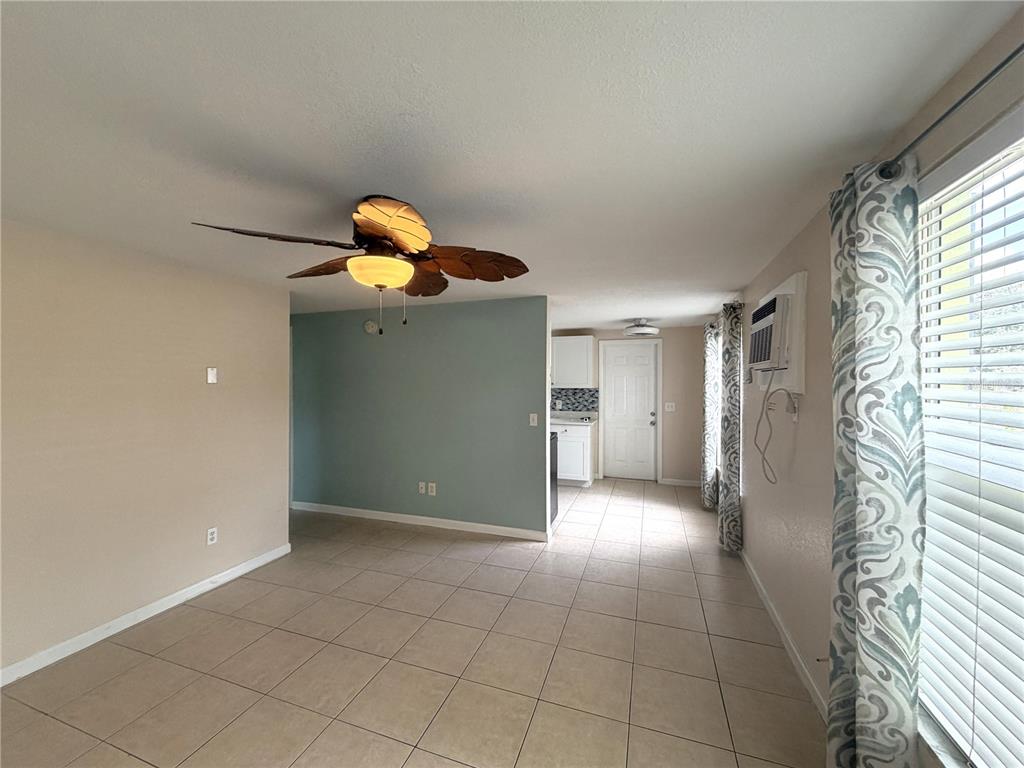 A tiled living room features a palm-leaf ceiling fan and an adjacent kitchen area — 634 DOGWOOD COURT, DUNEDIN, FL