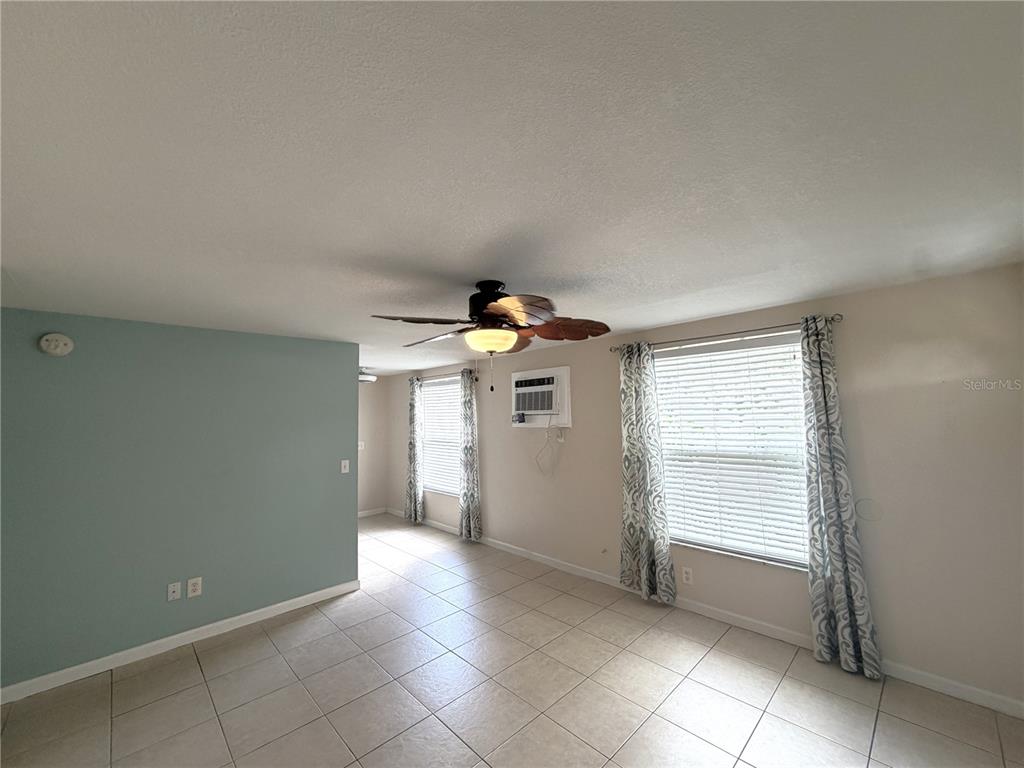 A living room features light-colored tile flooring, a ceiling fan, and a window air conditioner — 634 DOGWOOD COURT, DUNEDIN, FL