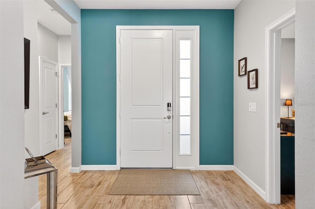 An entryway features a white front door, a teal accent wall, and wood-look tile flooring — 887 LADY BIRD LANE, ORANGE CITY, FL