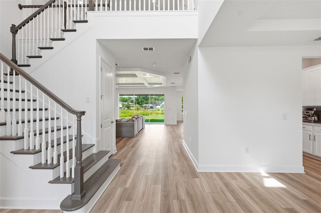 A foyer with light wood flooring leads to a staircase and a view of the backyard — 3321 LUMBER FALLS DRIVE, PLANT CITY, FL