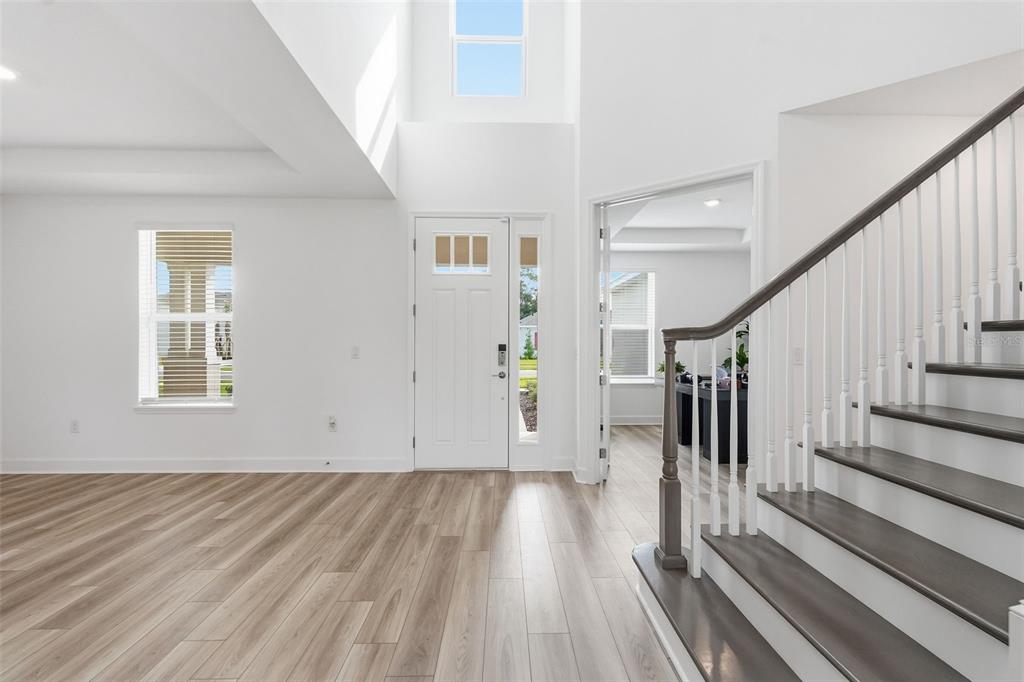 A bright entryway features light wood flooring, a white front door, and a wooden staircase — 3321 LUMBER FALLS DRIVE, PLANT CITY, FL