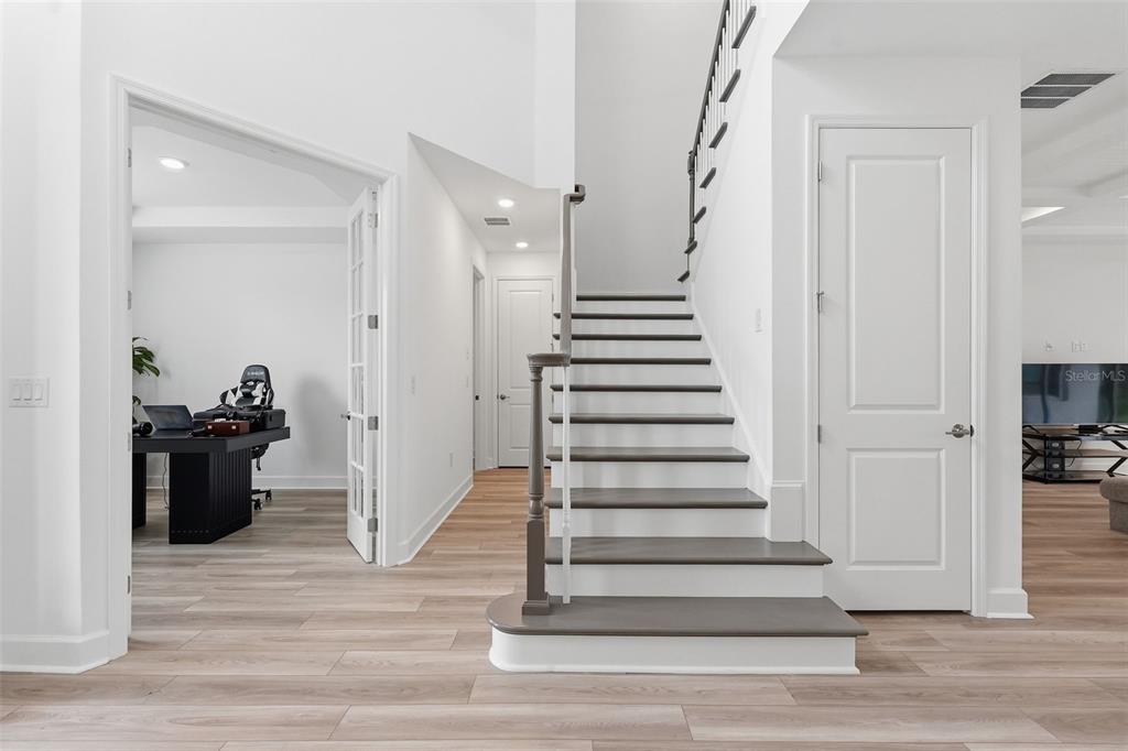 A staircase with dark treads and white risers stands between a home office and a doorway — 3321 LUMBER FALLS DRIVE, PLANT CITY, FL