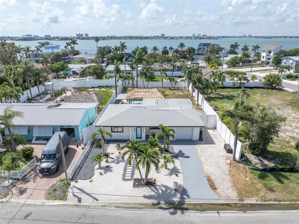 An aerial view shows a single-story house with a gray roof, palm trees, and driveway — 855 BOCA CIEGA ISLE DRIVE, ST PETE BEACH, FL