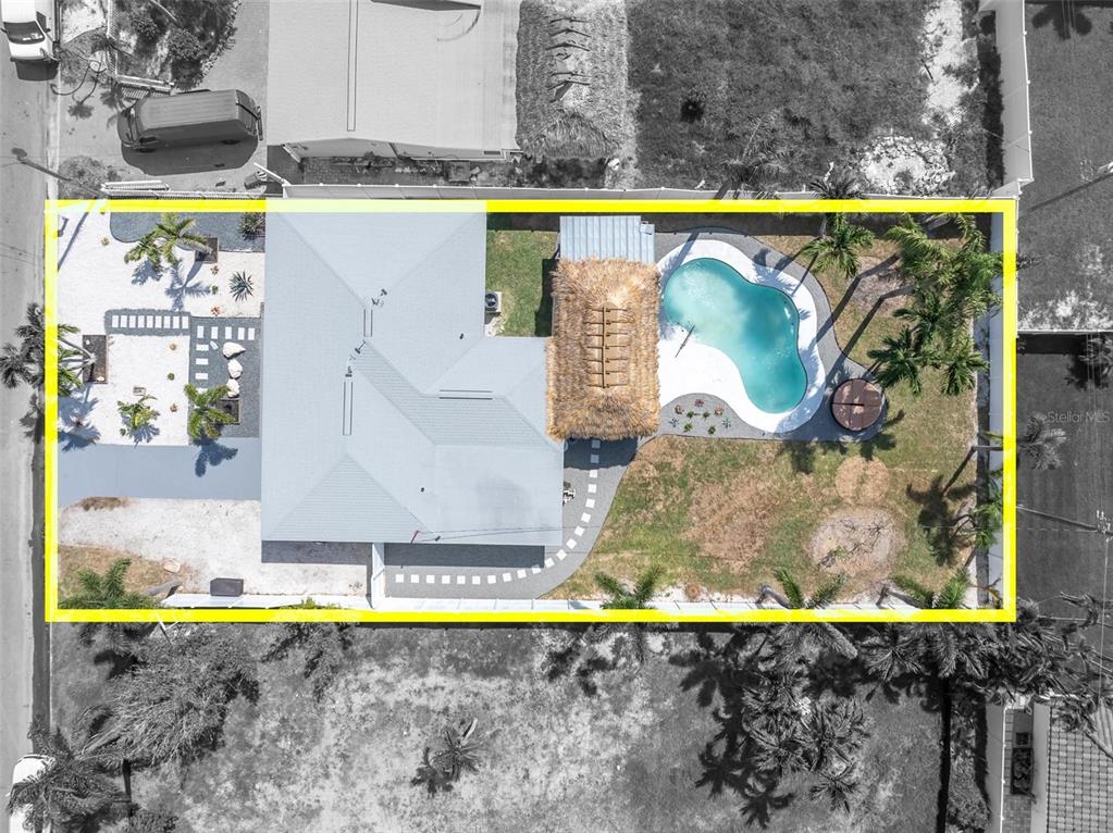 An aerial view shows a house with a metal roof, a pool, and a tiki hut — 855 BOCA CIEGA ISLE DRIVE, ST PETE BEACH, FL