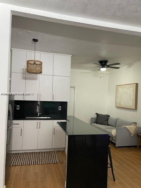 A kitchen with white cabinets and a black countertop opens into a living area — 7149 Bay Dr # 2, Miami Beach FL 33141, MIAMI BEACH, FL