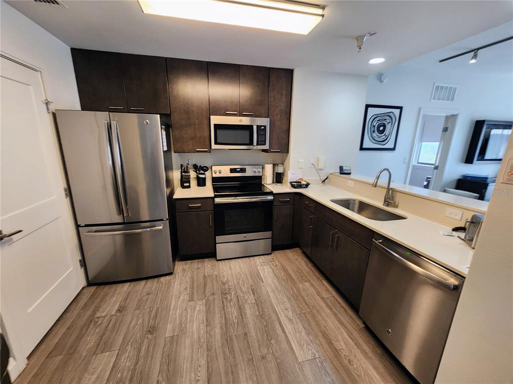 A kitchen features stainless steel appliances, dark wood cabinets, and light countertops — 14501 GROVE RESORT AVENUE UNIT 3737, WINTER GARDEN, FL