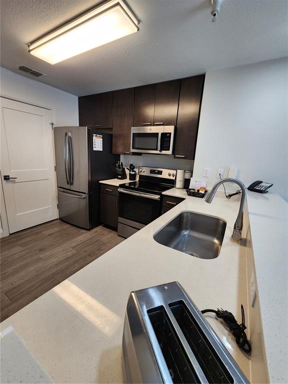 A kitchen features dark wood cabinets, stainless steel appliances, and white quartz countertops — 14501 GROVE RESORT AVENUE UNIT 3737, WINTER GARDEN, FL