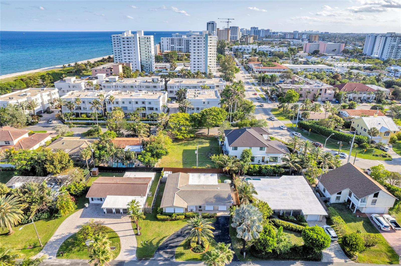 An aerial view shows residential homes, lush landscaping, and high-rise buildings along a coastal beach — 3404 Barton Road, Pompano Beach FL 33062, POMPANO BEACH, FL