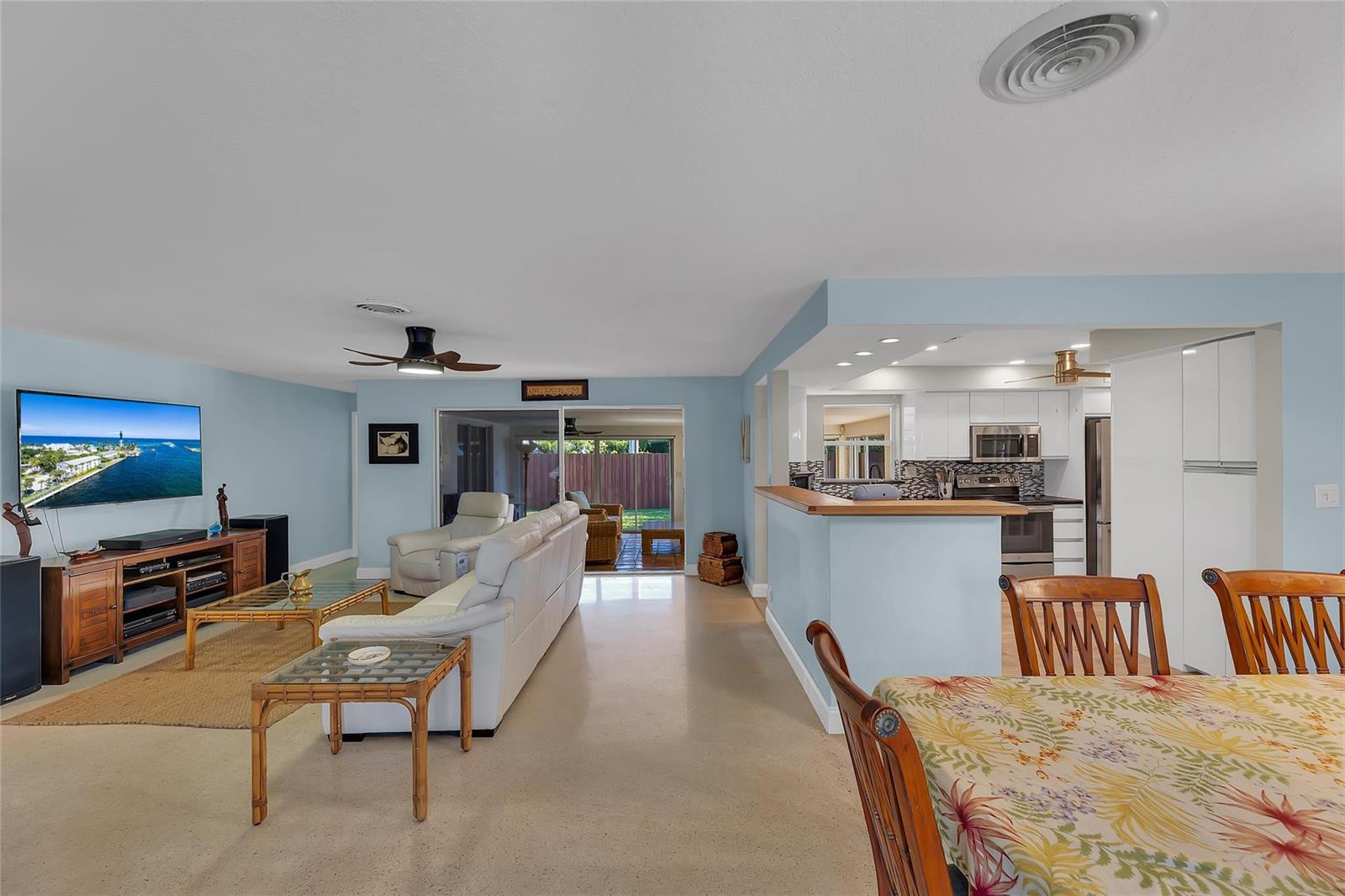 An open-concept living room and kitchen with light blue walls and light-colored flooring — 3404 Barton Road, Pompano Beach FL 33062, POMPANO BEACH, FL
