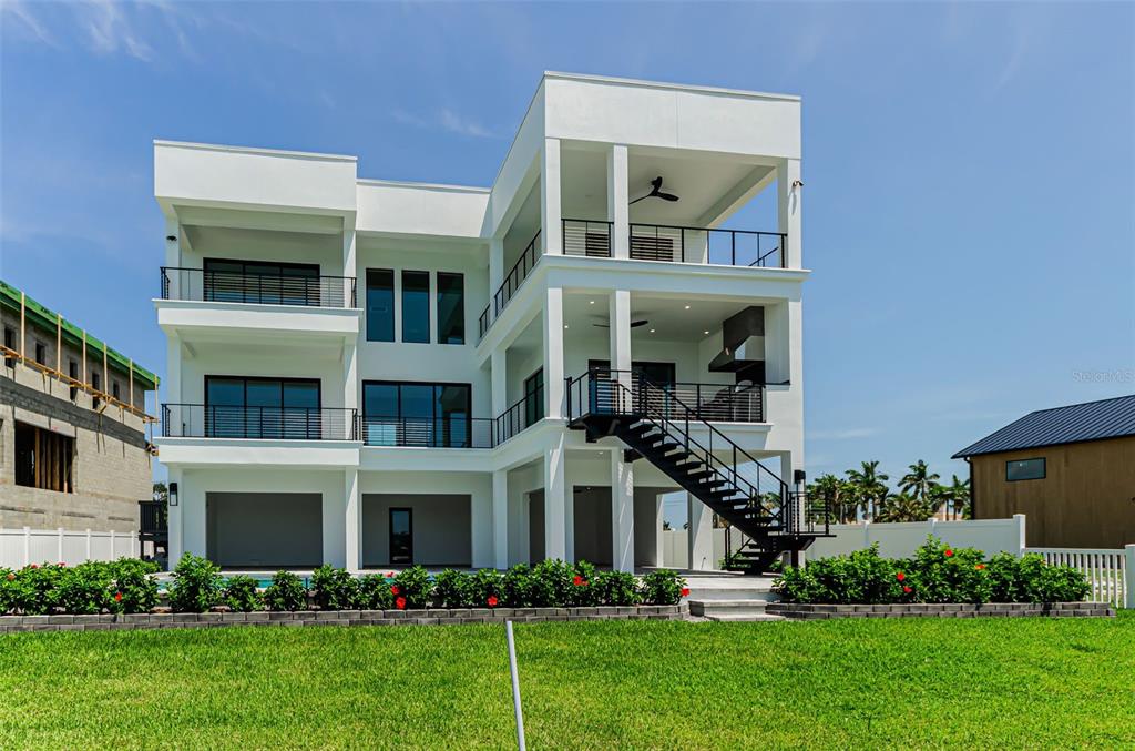 A three-story modern white house features multiple balconies, an external staircase, and a backyard pool — 43 DOLPHIN DRIVE, TREASURE ISLAND, FL