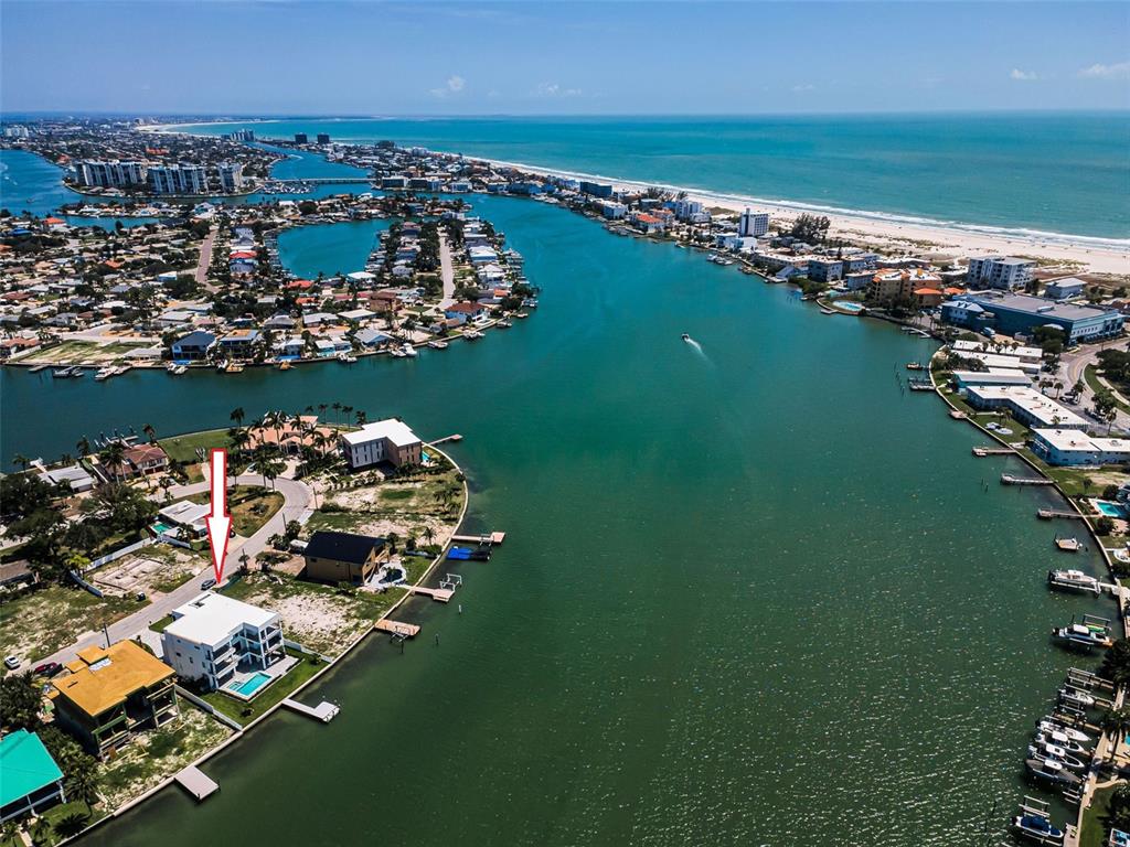 An aerial view shows a waterfront property with a white house and pool — 43 DOLPHIN DRIVE, TREASURE ISLAND, FL