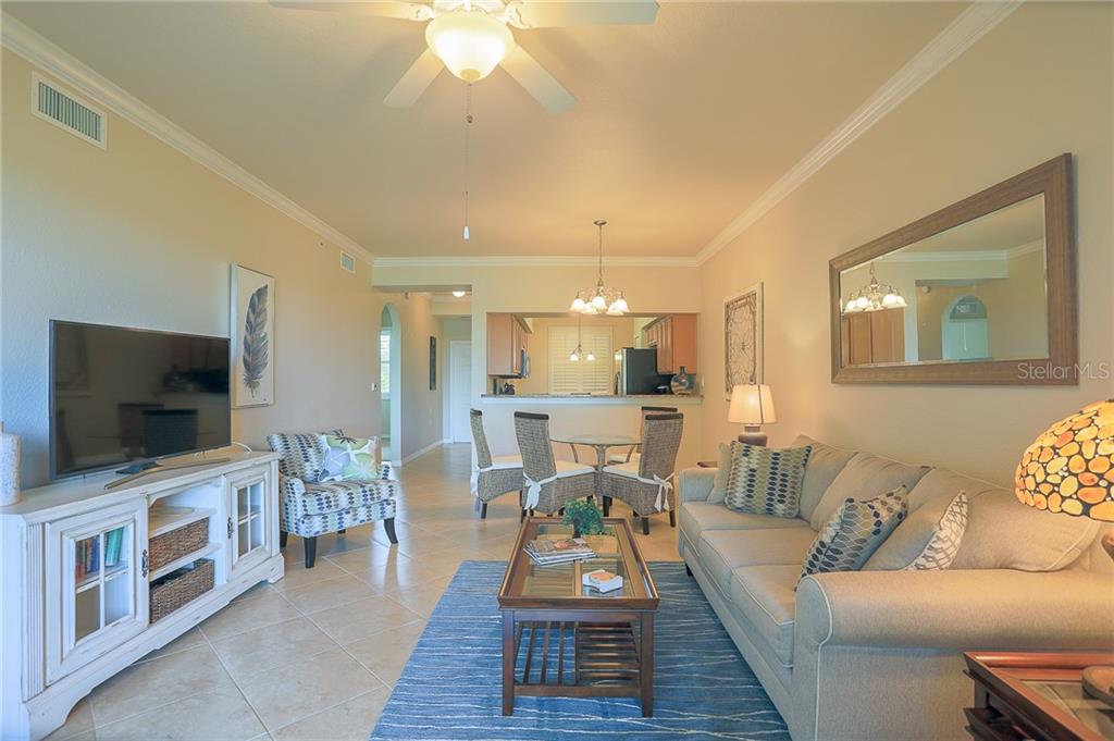 A living room with tile floors, a ceiling fan, a sofa, and a dining area — 8205 GRAND ESTUARY TRAIL UNIT 105, BRADENTON, FL