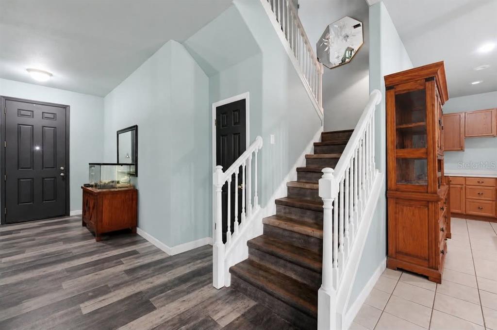 An entryway features a staircase with dark wood treads, white railings, and light blue walls — 2203 BLACKWOOD DRIVE, MULBERRY, FL