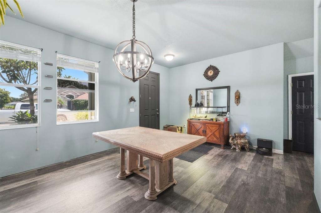 A dining room with light blue walls, wood-look flooring, a large table, and a chandelier — 2203 BLACKWOOD DRIVE, MULBERRY, FL