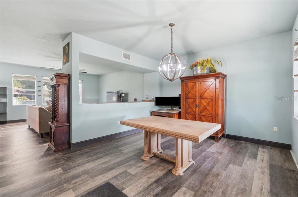 A dining room features wood-look flooring, a large wooden table, and a tall wooden cabinet — 2203 BLACKWOOD DRIVE, MULBERRY, FL