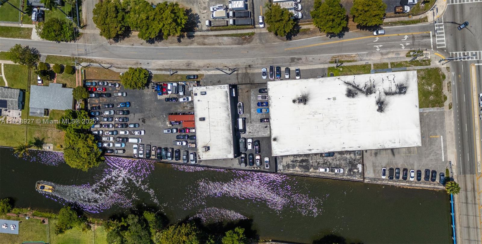 Aerial view of a commercial property with two buildings, a parking lot, and a canal — 8700 NW 7th Ave, Miami FL 33150, MIAMI, FL