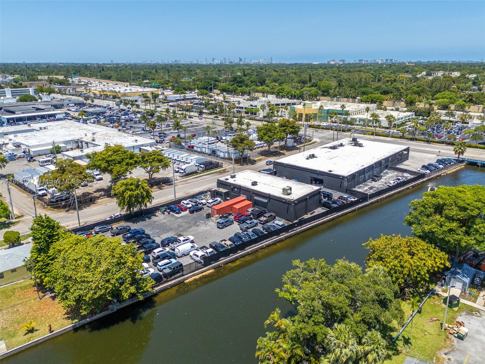 An aerial view shows a commercial building with a parking lot adjacent to a canal — 8700 NW 7th Ave, Miami FL 33150, MIAMI, FL