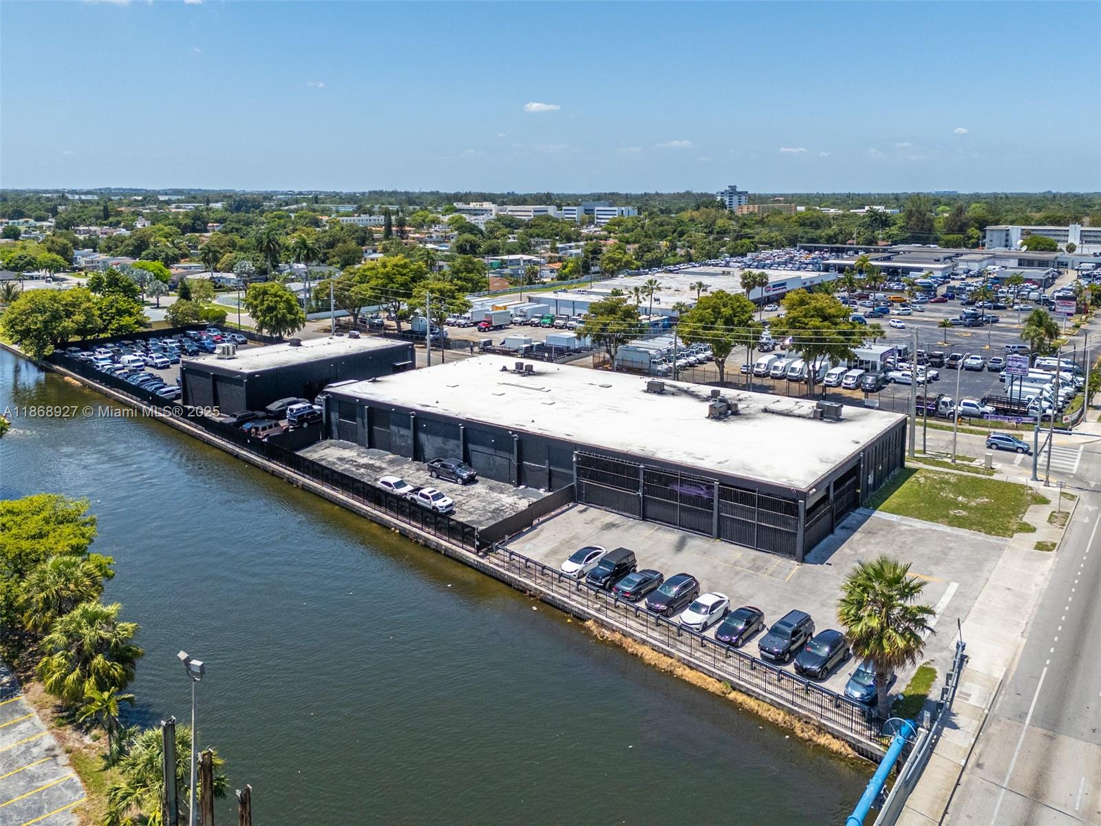 An aerial view shows a commercial building with a flat roof adjacent to a canal — 8700 NW 7th Ave, Miami FL 33150, MIAMI, FL