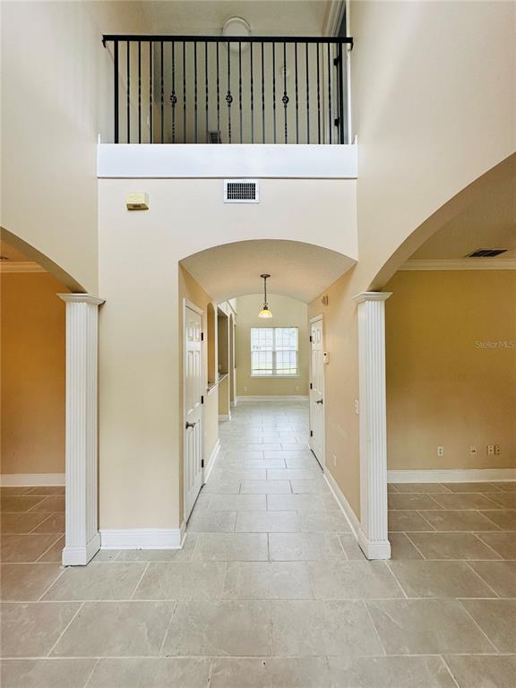 A two-story foyer features tiled floors, white columns, and a black metal balcony railing — 438 PALM DRIVE, SANFORD, FL