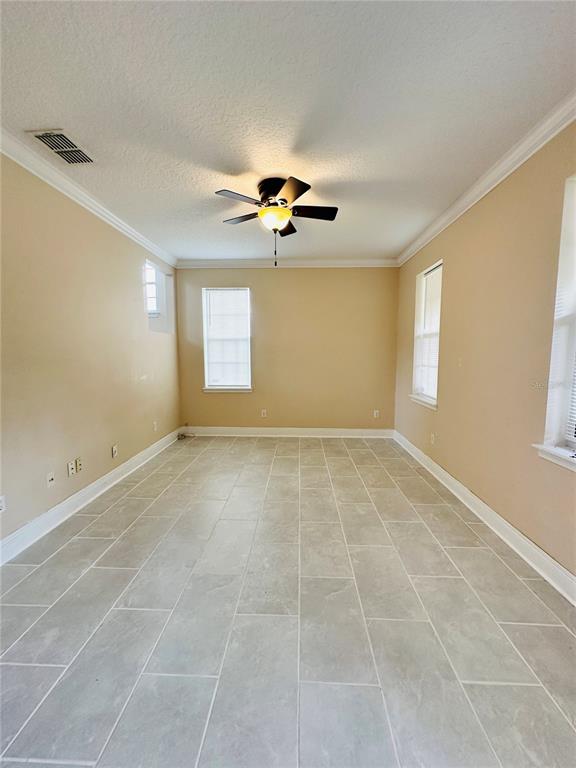 An empty room features light-colored tile flooring, beige walls, and a ceiling fan — 438 PALM DRIVE, SANFORD, FL