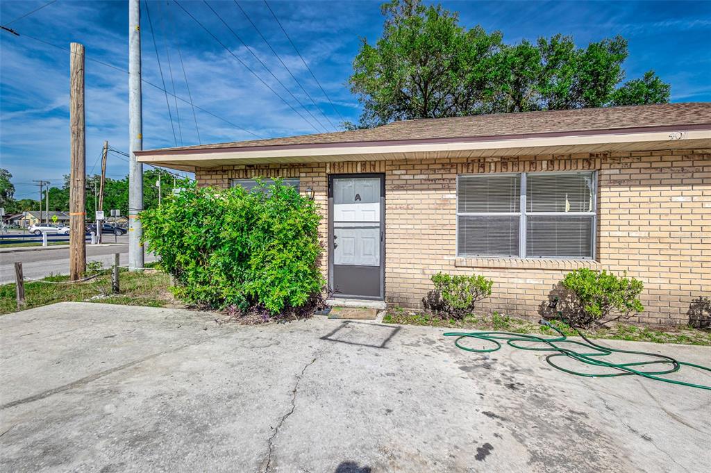 A single-story brick building with a concrete driveway and a green bush in front — 401 BIG CEDAR WAY UNIT A, BRANDON, FL