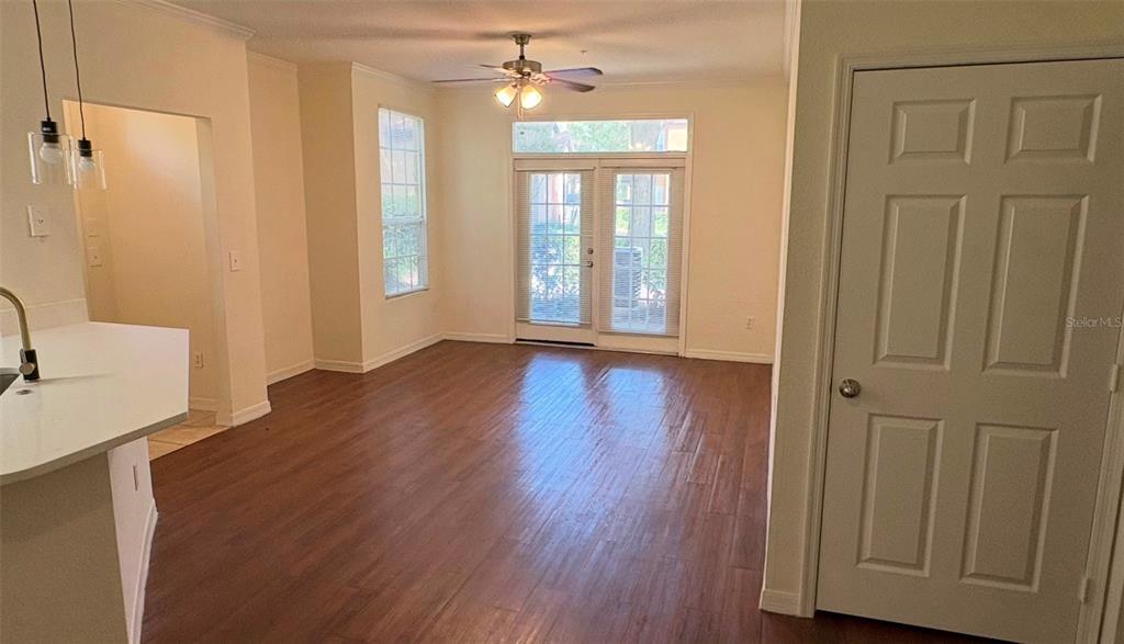 An interior view of a room with wood-look flooring, a ceiling fan, and glass doors — 6348 RALEIGH STREET UNIT 1304, ORLANDO, FL